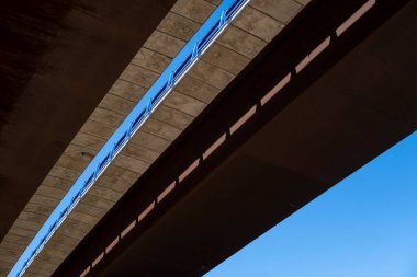 Mavi arka planı olan bir otoyolda yükseltilmiş bir köprü.