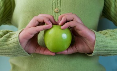 Yeşil elma tutan bir el.