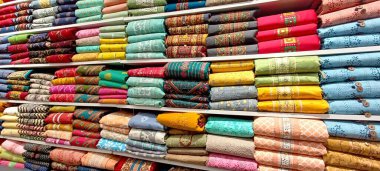 Renkli bir tekstil tasarımı bir mağazada raflara dizilmiş.