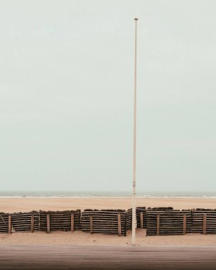 Deauville, Normandie, Fransa 'da tahta çitli kumlu bir sahilin dikey görüntüsü.