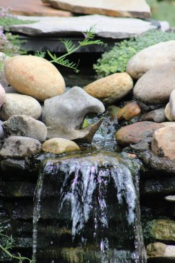 Farklı taşlardan oluşan küçük bir şelalenin dikey görüntüsü.