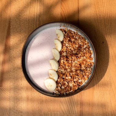 Tahta bir masada mısır gevreği ve muzlu kahvaltı kasesinin yakın çekimi.