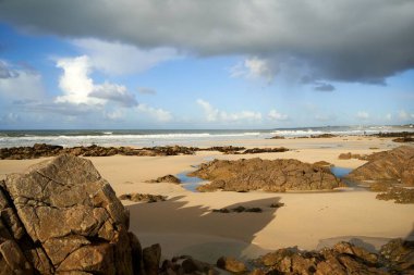 Bulutlu gökyüzünün altındaki kayalık deniz manzarası