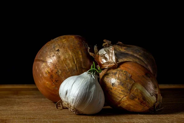 Closeup Two Unpeeled Brown Onions Garlic Wooden Table Black Background — Stock Photo, Image