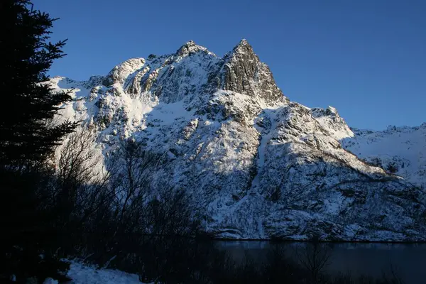 靠近河边的一座山在冬天被雪覆盖着 — 图库照片