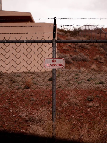 A vertical shot of a sign \'No trespassing\' on a metal fence in a rural area