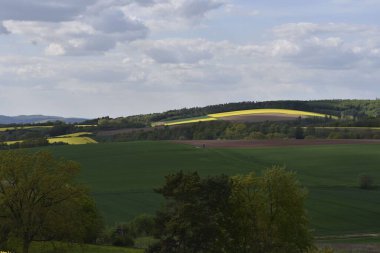 Parlak gökyüzünün altında yeşil bir vadi ve tepeler.