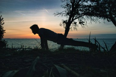 Wight Adası 'ndaki bir sahilde, çimenli bir yüzeye el kalası yapan genç bir adamın silüeti.