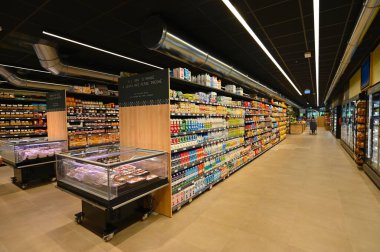 Çeşitli mallarla dolu süpermarket rafları.