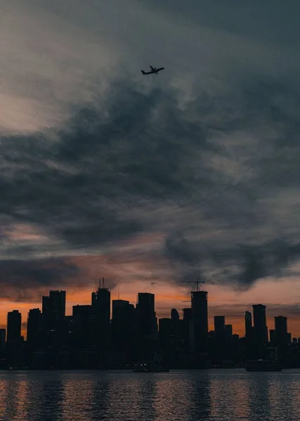 Ett Vertikalt Skott Ett Flygplan Flygning Ovanför Skyline Solnedgången — Stockfoto