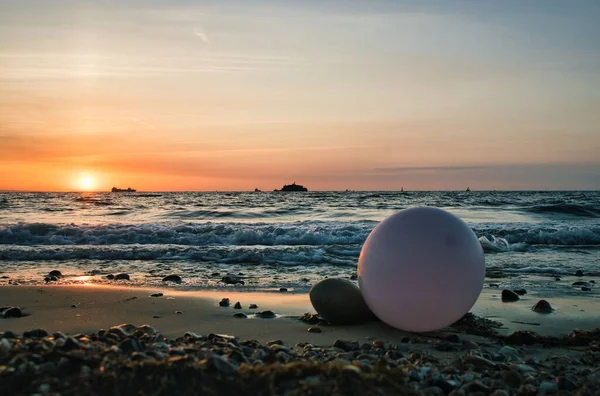Růžový Balón Ležící Skalnaté Pláži Mořskými Vlnami Západem Slunce Pozadí — Stock fotografie