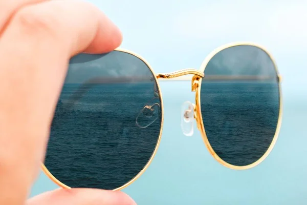 Samica Trzymająca Okulary Przeciwsłoneczne Tle Błękitnego Nieba Spokojne Niebieskie Morze — Zdjęcie stockowe