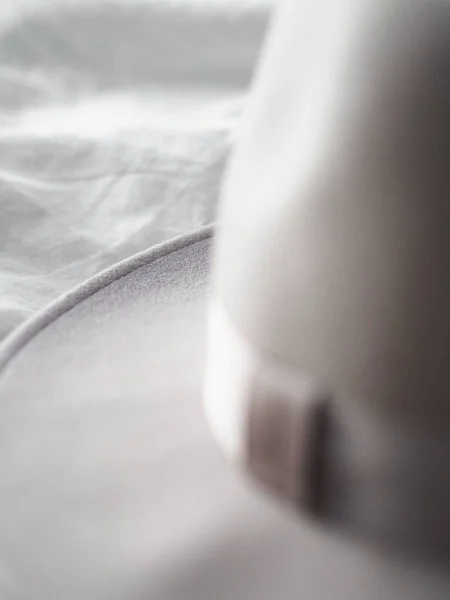 白いベッドシートの上のファッショナブルな帽子の垂直ショット — ストック写真
