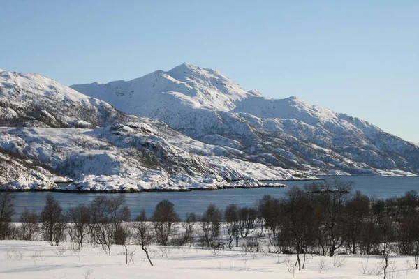 靠近河边的一座山在冬天被雪覆盖着 — 图库照片