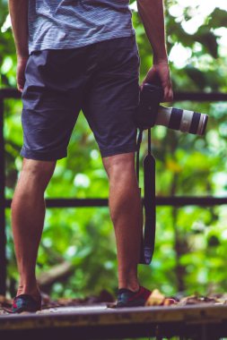 Kamerayı eliyle tutan kısa boylu bir adamın dikey görüntüsü..