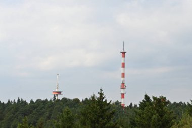 Bir televizyon kulesi ve kasvetli bir günde yaprak döken ağaçlar.