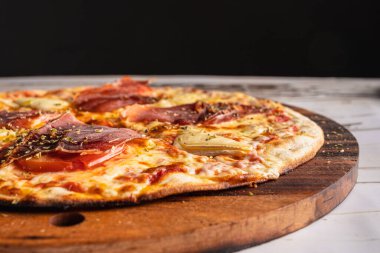 Ahşap bir masada leziz bir İspanyol jambonlu pizzası.
