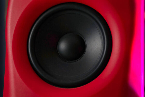 A close-up shot of a black speaker surrounded by a red surface.