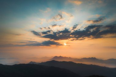 Gün batımı gökyüzünün altındaki dağların doğal manzarası.