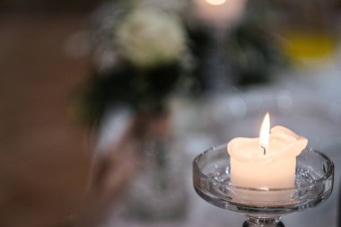 Yanan küçük beyaz bir mumun yakın plan çekimi.