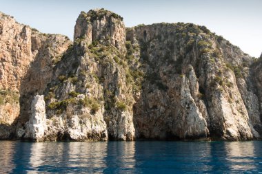 İtalya 'nın Centola kentindeki Marinella' da açık bir gökyüzüne karşı mavi sudaki kayalık uçurumların güzel manzarası.