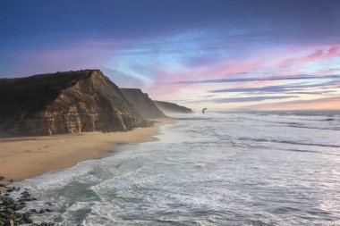 Denizin köpüklü sularının ve Praia de Sao Juliao, Portekiz 'in sarp kayalıklarının hava görüntüsü.