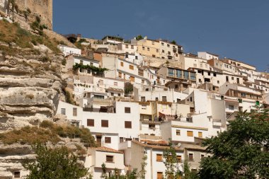 Alcala del Jucar şehrinin manzarası bulutsuz bir gökyüzüne karşı tepenin üzerindeki binalar.