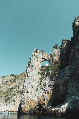 İtalya 'nın Centola kentindeki Marinella' da açık bir gökyüzüne karşı mavi sudaki kayalık uçurumların güzel manzarası.
