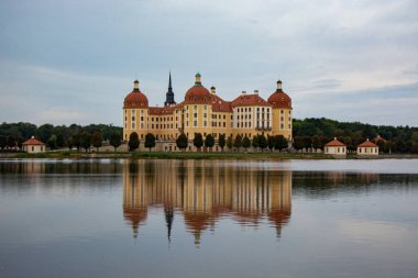 Almanya 'da bulutlu bir gökyüzüne karşı Moritzburg kalesinin güzel manzarası göl suyuna yansıyor.