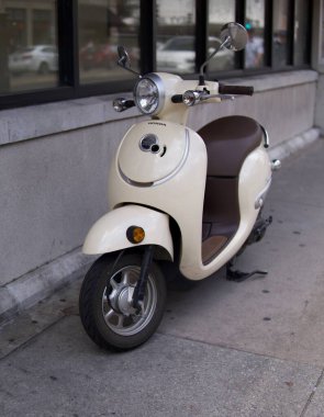 Savannah, Georgia, ABD 'de kaldırımda park etmiş bronz bir scooter' ın dikey çekimi.