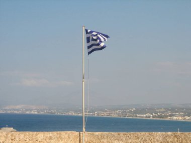 Arka planda deniz olan rüzgârlı bir Yunan bayrağının güzel manzarası