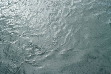 Göl suyuna yakın çekim. Güneş ışığı yansıyor.