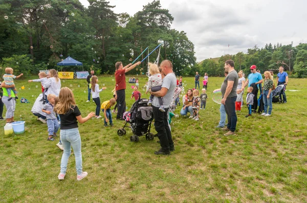 ポーランドのマルタ公園で彼らを捕まえようとしている幸せな子供たちのために大きなシャボン玉を作っている男 — ストック写真