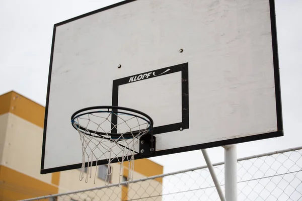 曇った空に対して黒と白のバスケットボールのフープの低角度ショット — ストック写真