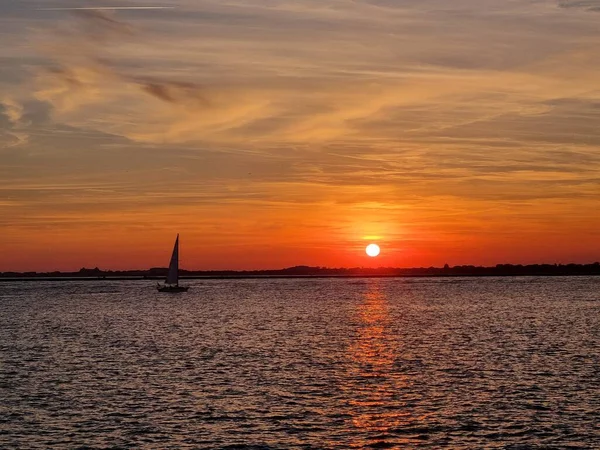 一张美丽的落日照片挂在一艘帆船上的海面上 — 图库照片