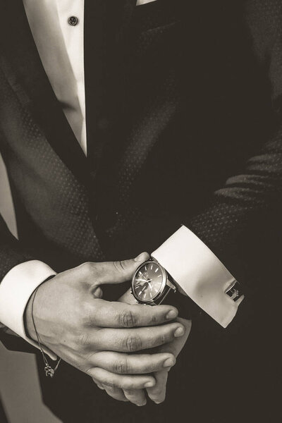 A vertical shot of a man wearing a classical suit with a watch on his wrist