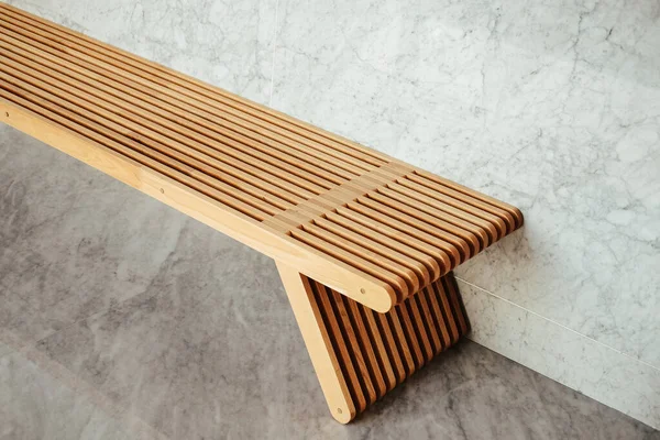木製のベンチの完璧なクローズアップショットは 大理石の壁を得ます — ストック写真