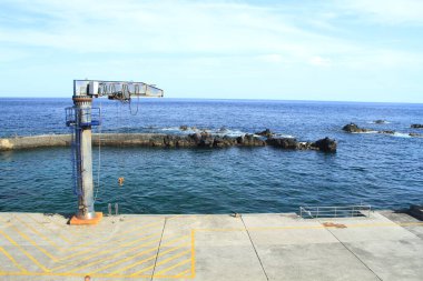 Deniz kenarında mavi bir arka planı olan taş bir rıhtımın güzel manzarası.