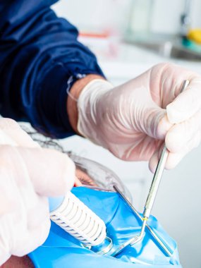 Bir dişçinin muayenehanesinde bir hastayla çalışan bir dişçi.