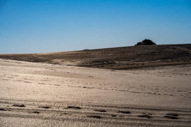 Güzel, tozlu bir çöl manzarası. Mavi gökyüzünün altında ayak sesleri.