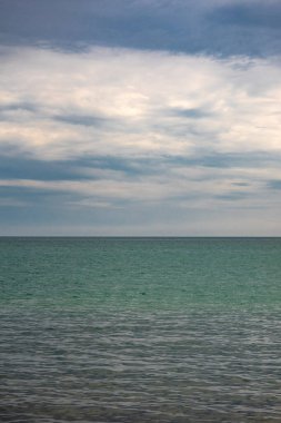 Bulutlu bir arkaplanda engin bir okyanusun dikey çekimi.