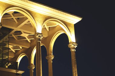 Gece karanlığında aydınlık, altın kemerli bir binanın alçak açısı.