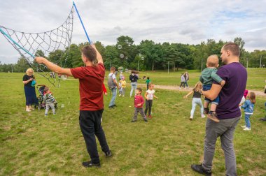 Polonya 'nın Malta Parkı' nda onları yakalamaya çalışan bir grup mutlu çocuk için büyük sabun köpükleri yaratan bir adam.