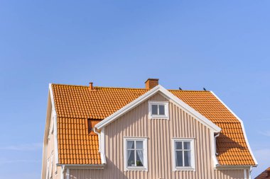 Pembe ve turuncu bir evin düşük açılı görüntüsü bulutsuz mavi bir gökyüzüne karşı güneşli bir günde