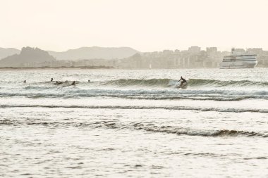 Kasvetli bir günde dalgaları yakalayan sörfçülerin güzel bir fotoğrafı.