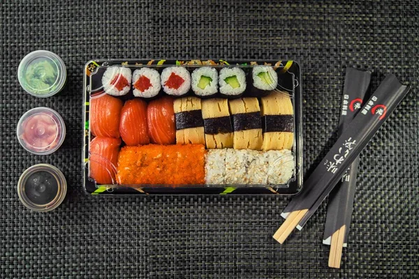 在黑色面料背景的筷子旁边的长方形盒子里 可以看到美味寿司的头像 — 图库照片