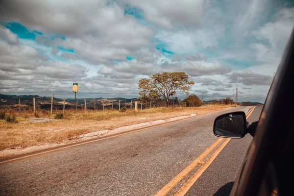 曇り空の下 畑に囲まれた道を走る車 — ストック写真