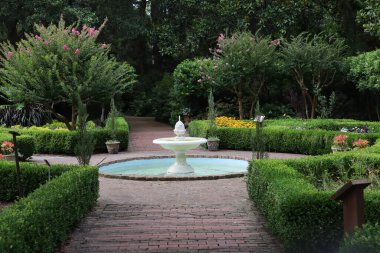 Ortasında beyaz bir çeşme olan güzel bir bahçe.