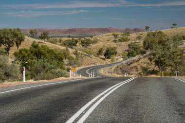 Vahşi bir manzaranın yanında bir yolun perspektif görüntüsü.