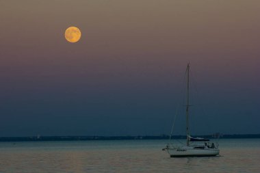 Macar gölü Balaton 'da bir yelkenli ve dolunay.